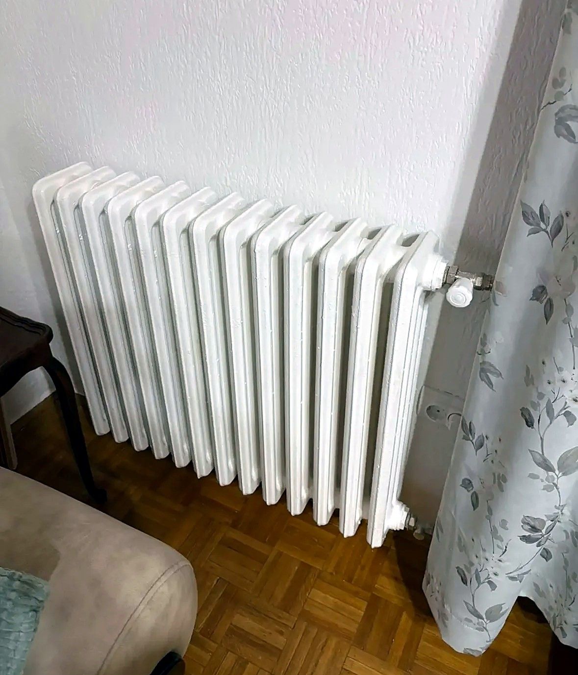 Beli liveni člankasti radijator u sobi sa parketom